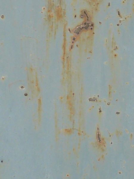Rusting metal door in light blue shade with spots and streaks of rust.